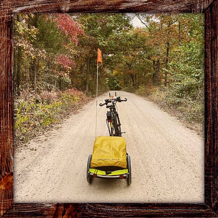 Photo, Day 47 of the TransAmerica Bicycle Trail, Mandy's bicycle and trailer on a gravel path cutting through a canopy of trees with bright autumn colors