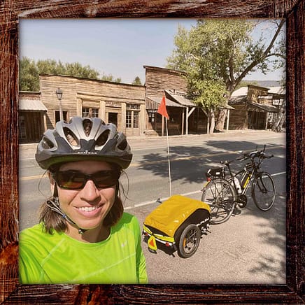 Photo, Day 19 of the TransAmerica Bicycle Trail, Mandy in Virginia City, Montana standing in front of a historic Western town with wooden storefronts