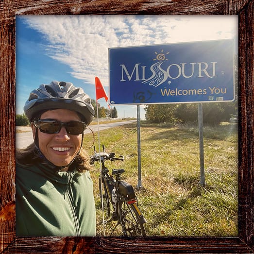Photo, Day 42 of the TransAmerica Bicycle Trail, Mandy with her bicycle and a sign that says "Missouri Welcomes You"