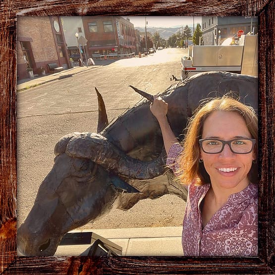 Photo, Day 09 of the TransAmerica Bicycle Trail, Mandy's grabbing the horn of a bronze water buffalo sculpture in Baker City Oregon
